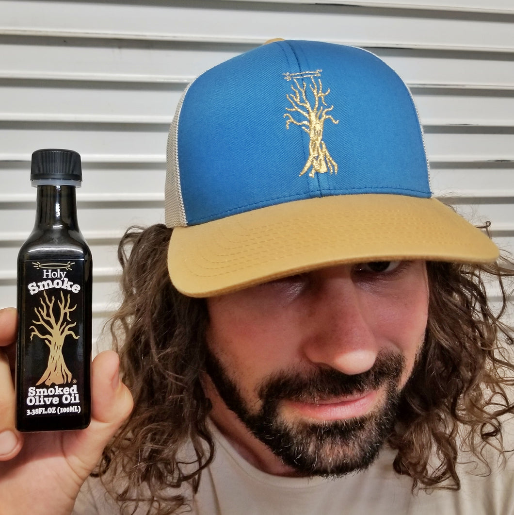 a doofus wearing a blue hat and holding a bottle of smoked olive oil